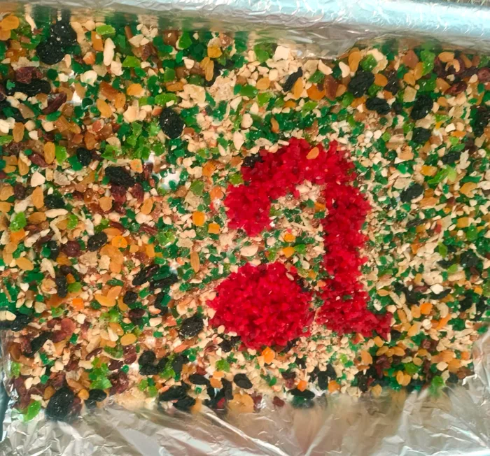 A tray of chopped dried fruit and nuts with a heart shape made of red cherries in the middle